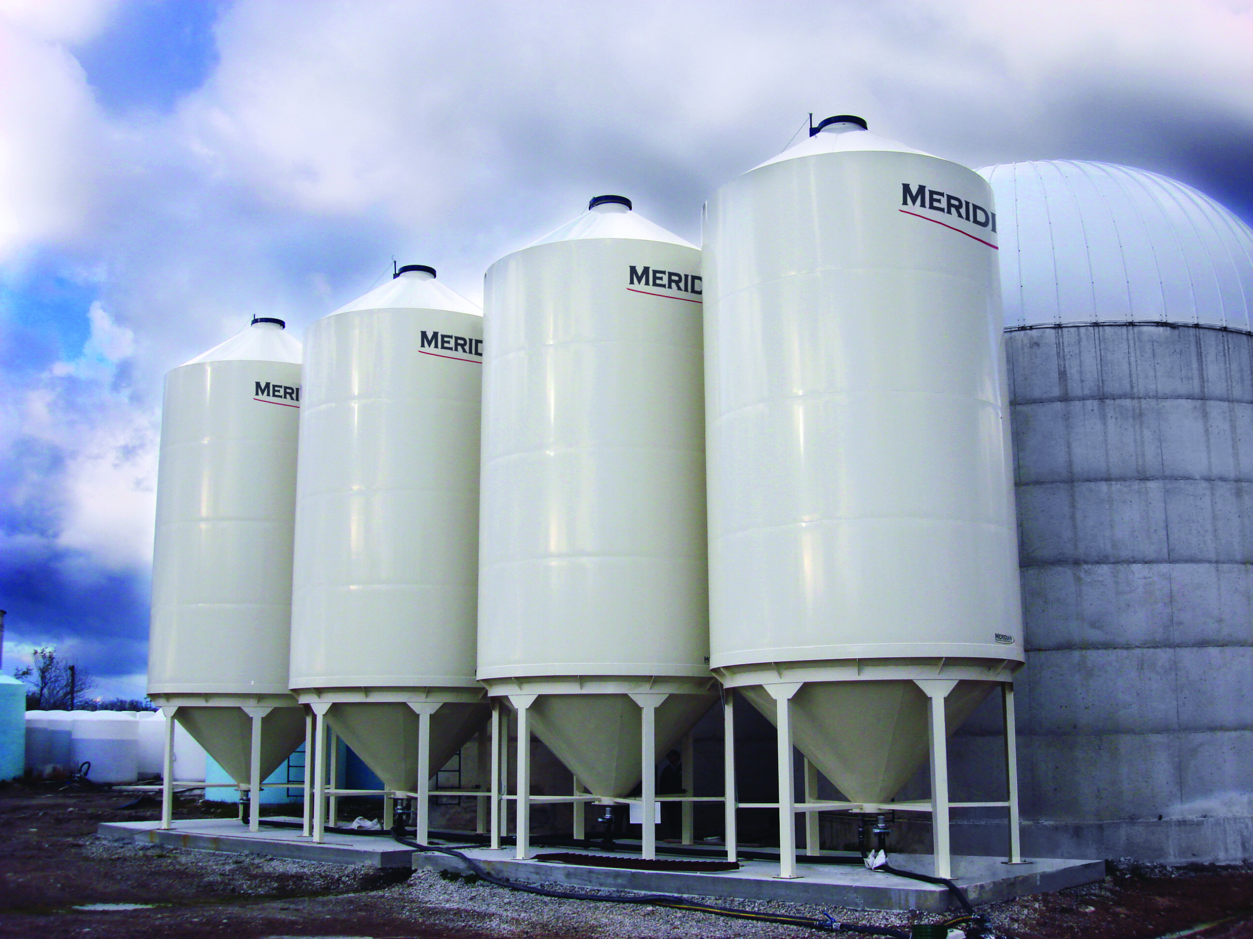 group of 4 liquid hopper bottom bins next to a concrete storage structure